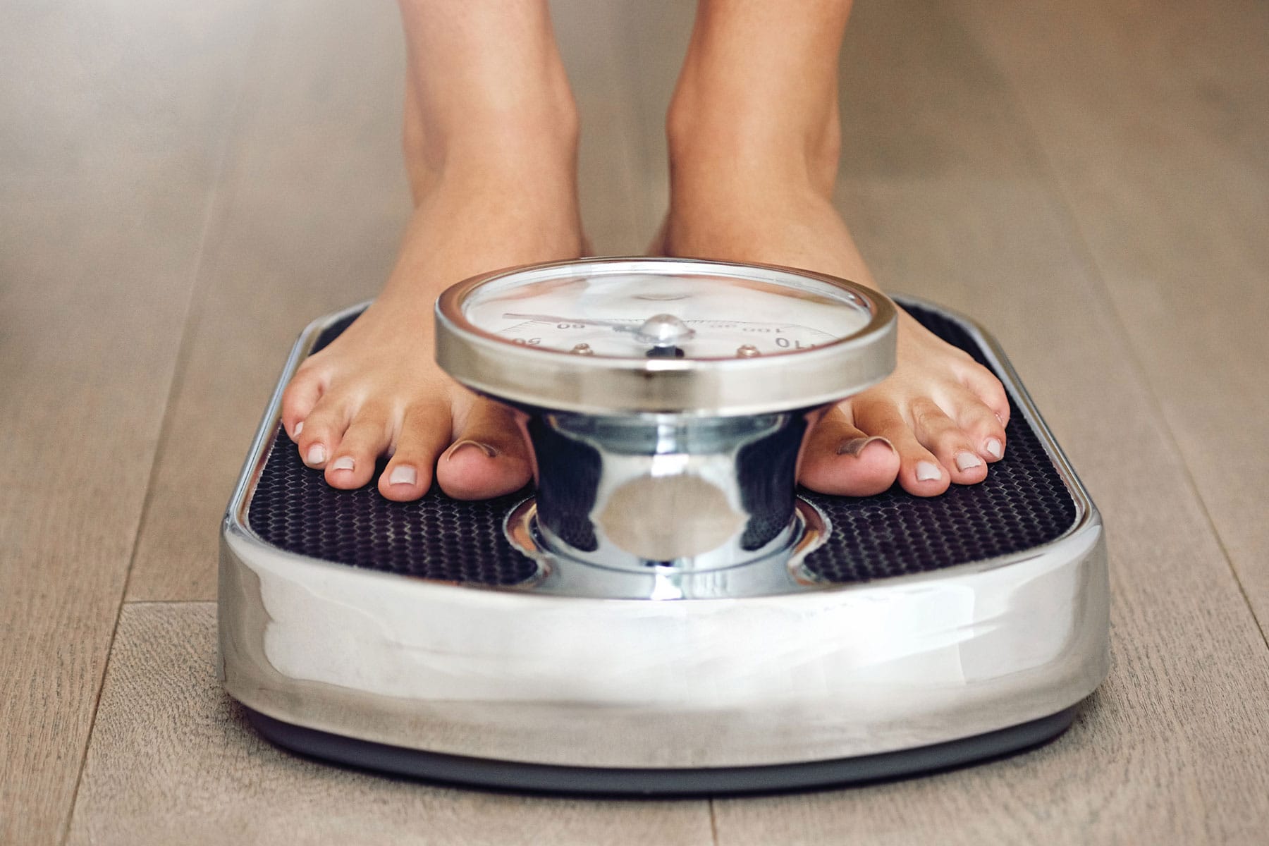 A person checking weight on a weighing scale.