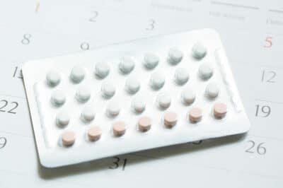 A leaf of birth control pills placed on a calendar page.