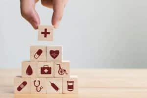 A person building a pyramid using blocks with medical icons on them.
