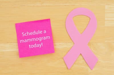 A pink ribbon and a sticky note to schedule a mammogram.
