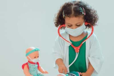 A child playing with dolls pretending to be a doctor.